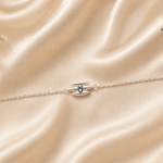 Trinetra 925 Silver Rakhi featuring a protective eye-inspired motif crafted in sterling silver with an adjustable chain, displayed on a luxurious beige satin background by Mohnaa Jewels.