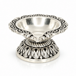 Mohnaa Shreepad 925 sterling silver decorative diya featuring an ornate scalloped rim, polished bowl, and intricately detailed pedestal base on a white background.

