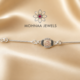 "Om 925 Silver Rakhi featuring a sacred Om symbol with sparkling stone embellishments on an adjustable sterling silver chain, elegantly displayed on a luxury satin background by Mohnaa Jewels."